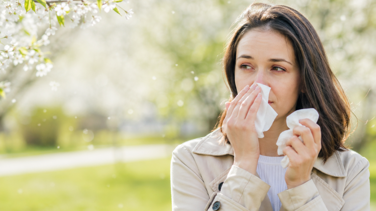 υναίκα με συμπτώματα αλλεργικής ρινίτιδας την άνοιξη σε εξωτερικό χώρο